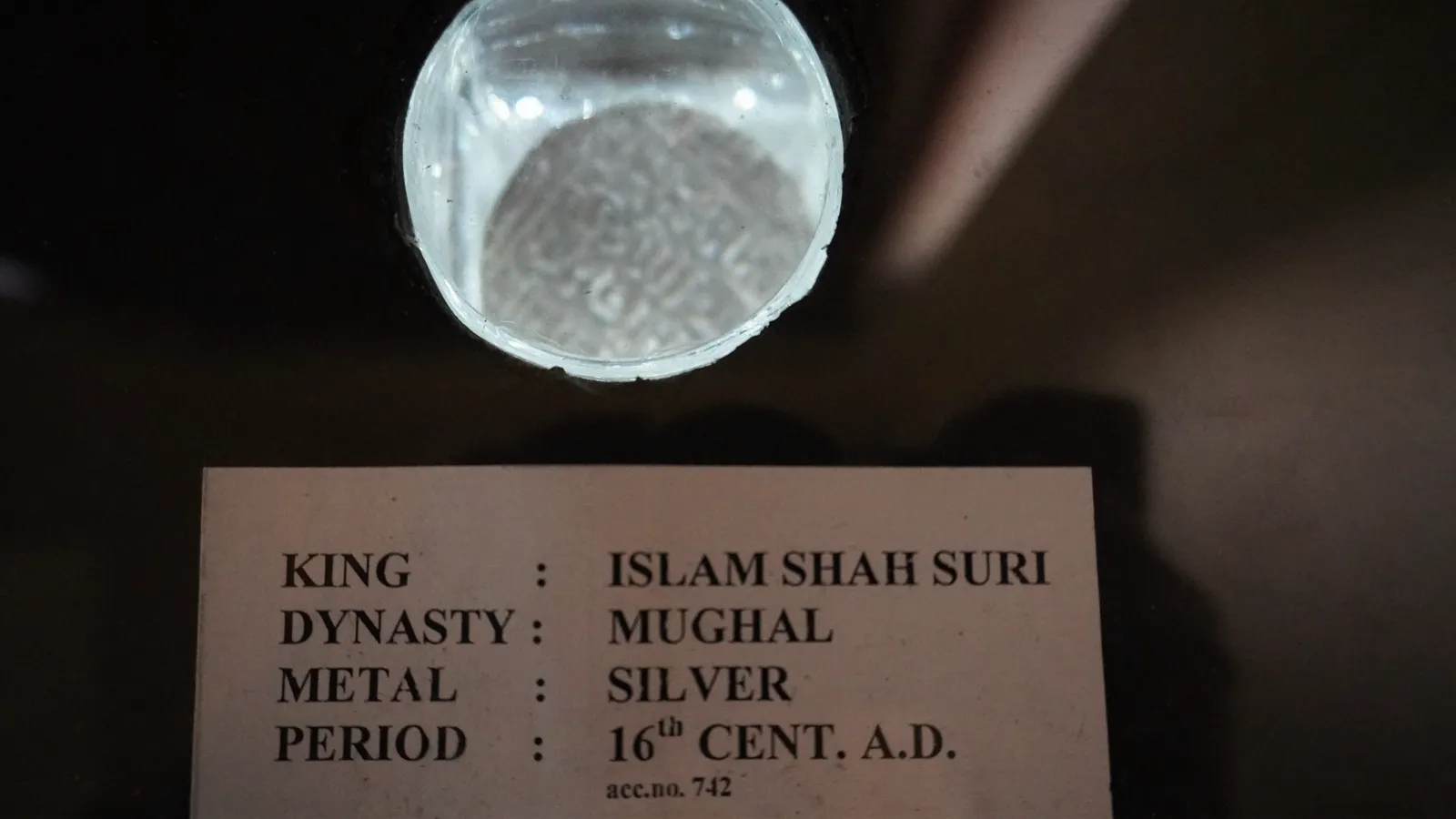 Silver coin of Islam Shah Suri, 16th century AD, under a magnifier