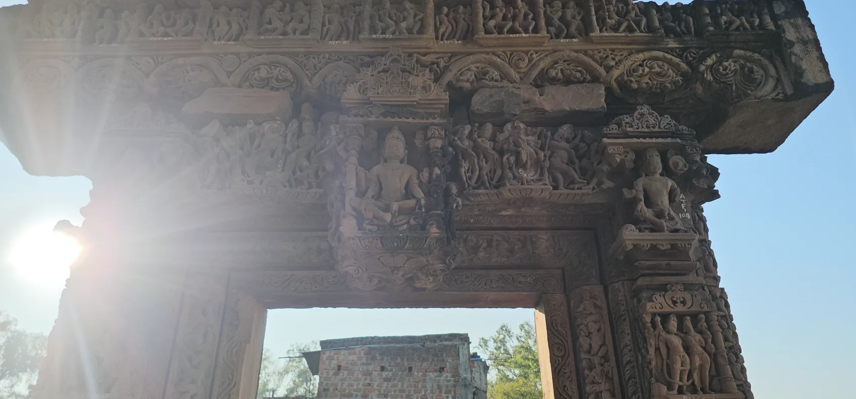 Afternoon sunlight through a ruined carved gateway at Gyaraspur