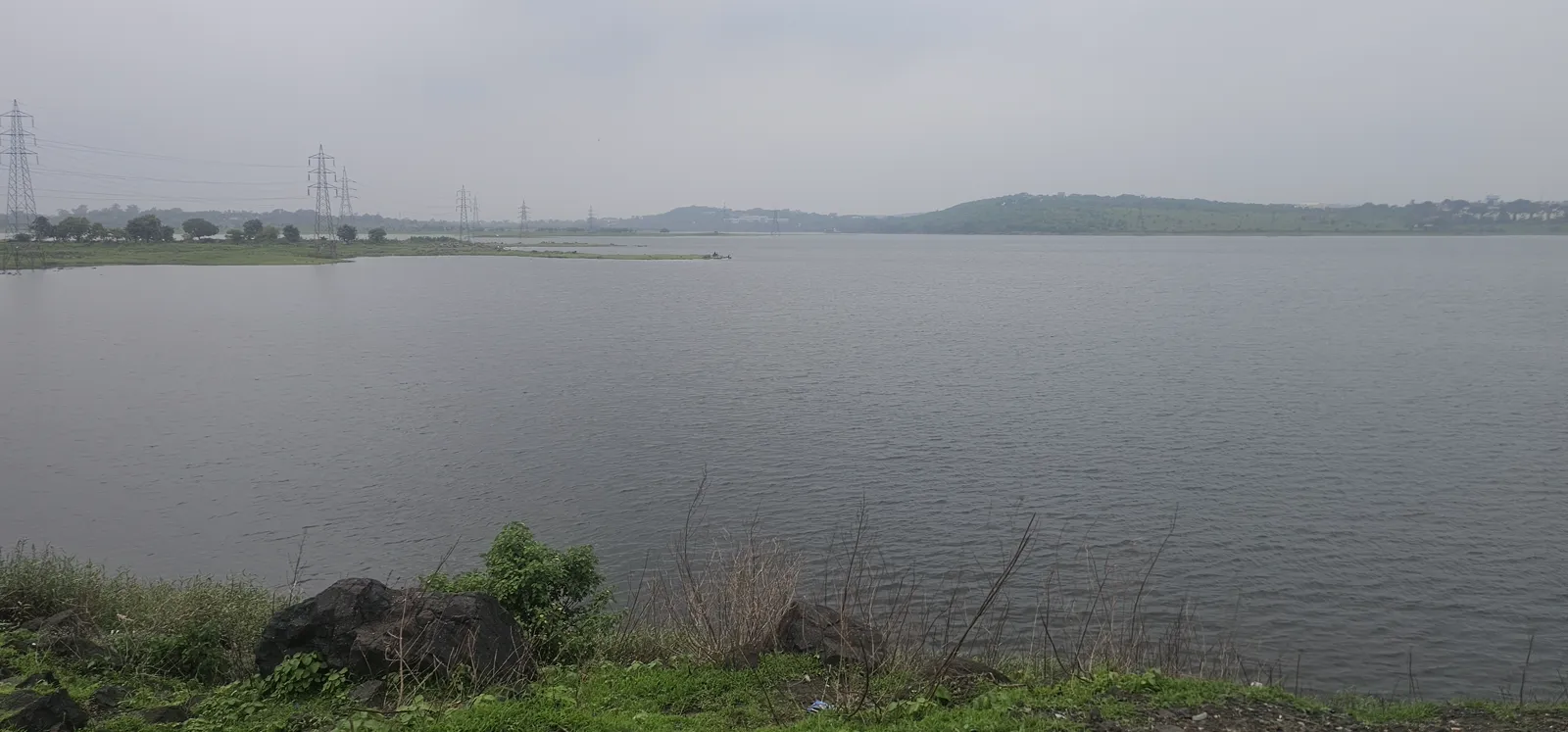 Grey monsoon water at Kaliasot with a soft line of green hills on the far bank