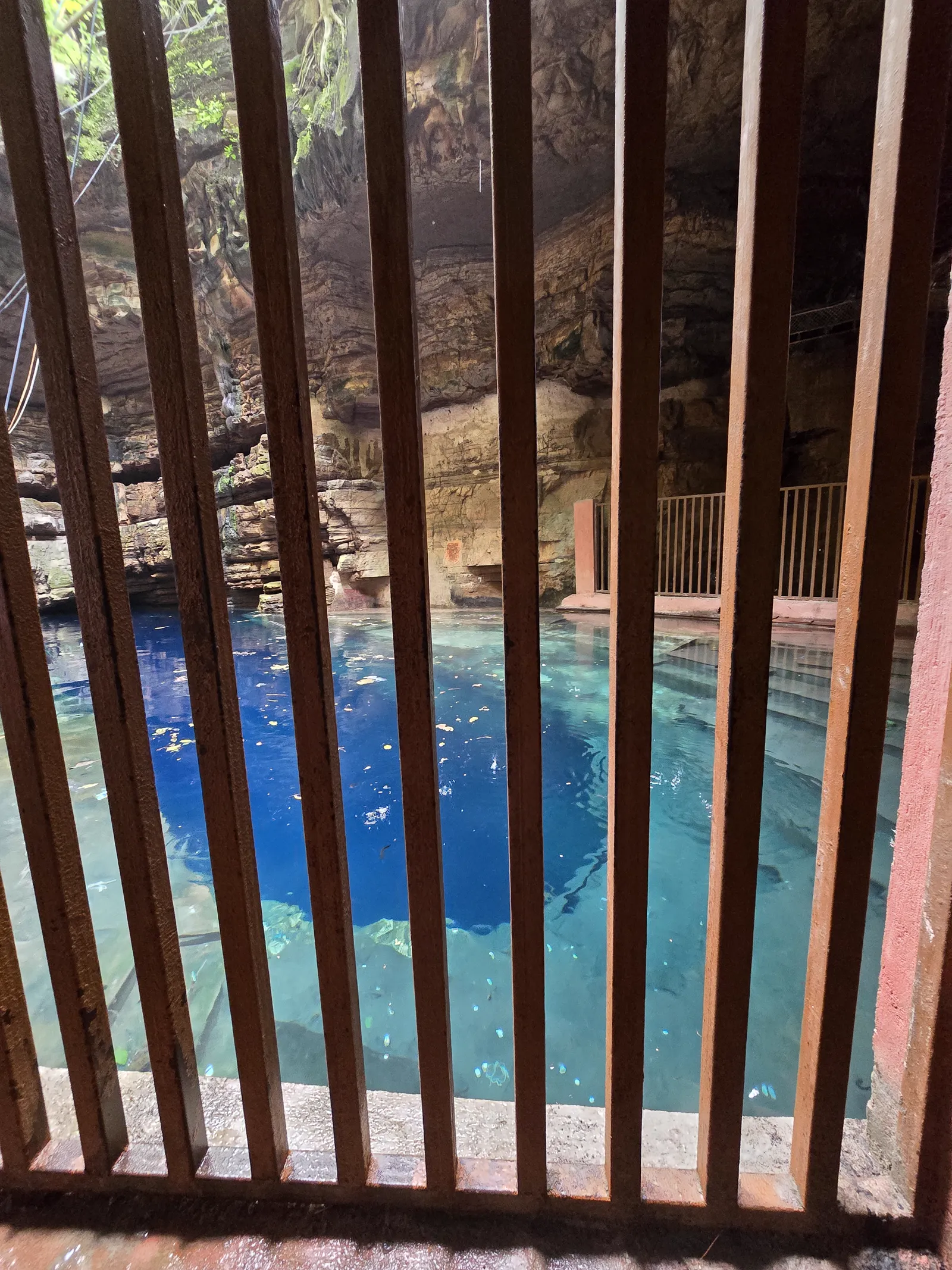 The contrast of red rock walls against the blue water at Bhimkund