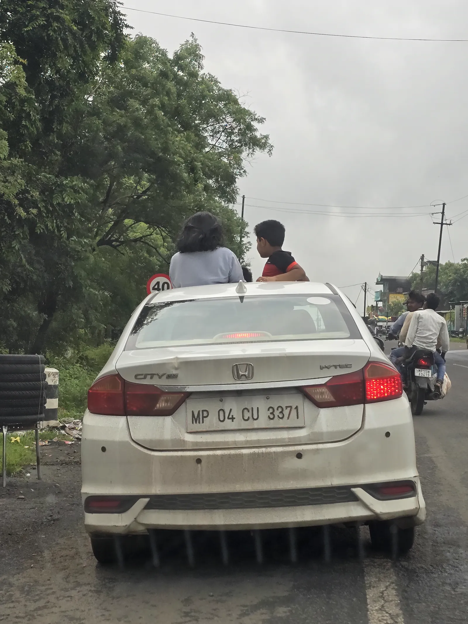 Two cars pulled over on the rain-soaked monsoon highway, seen from behind