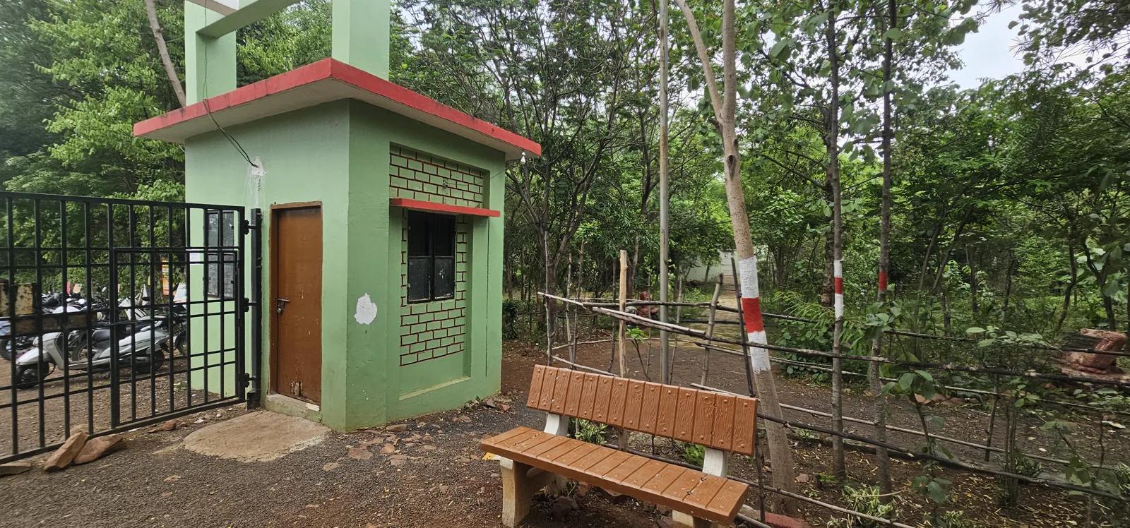 The green gate-house and a wooden bench at the Laharpur park entrance