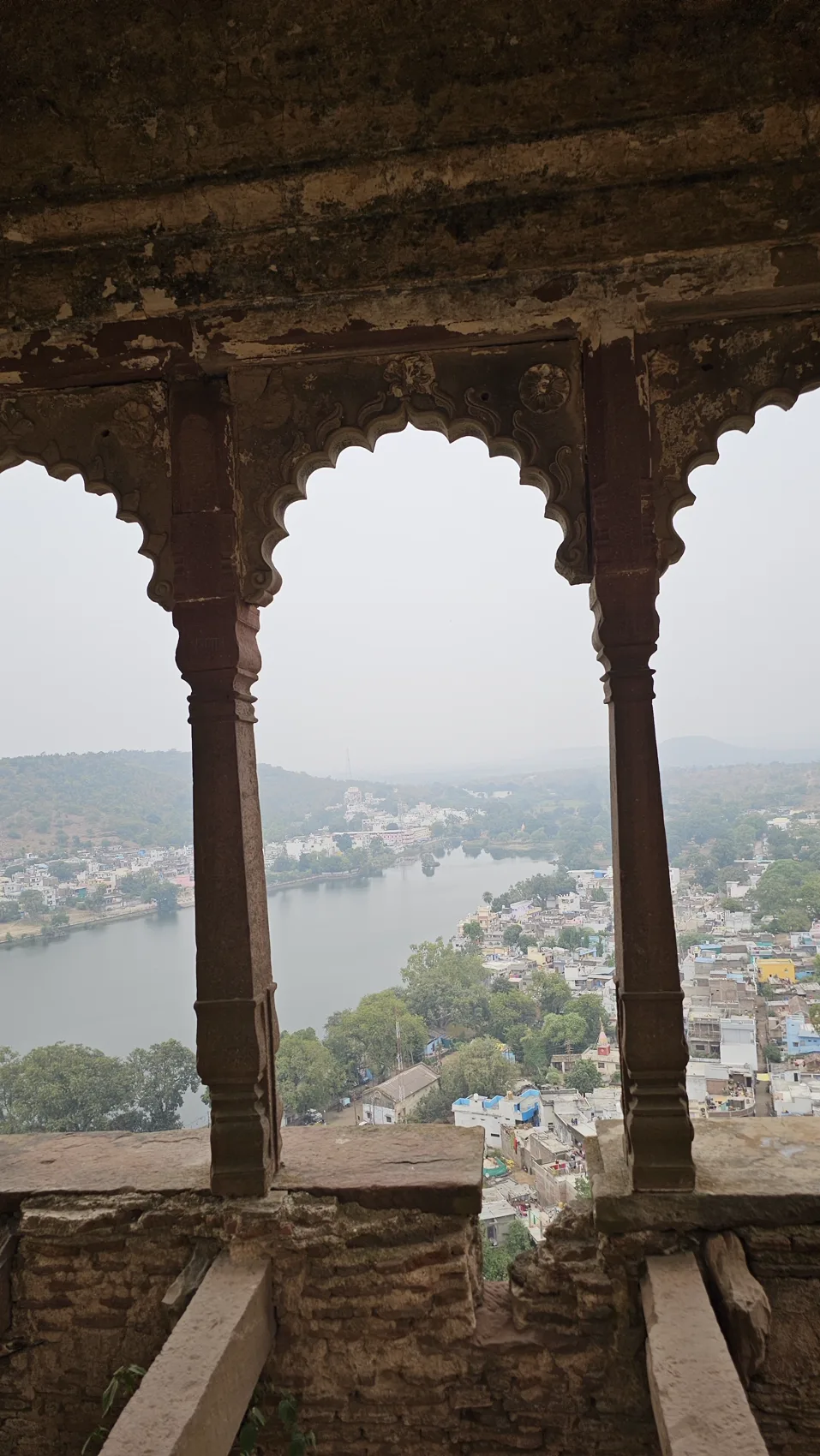 A carved jharokha window framing Parasram Sagar lake and the town