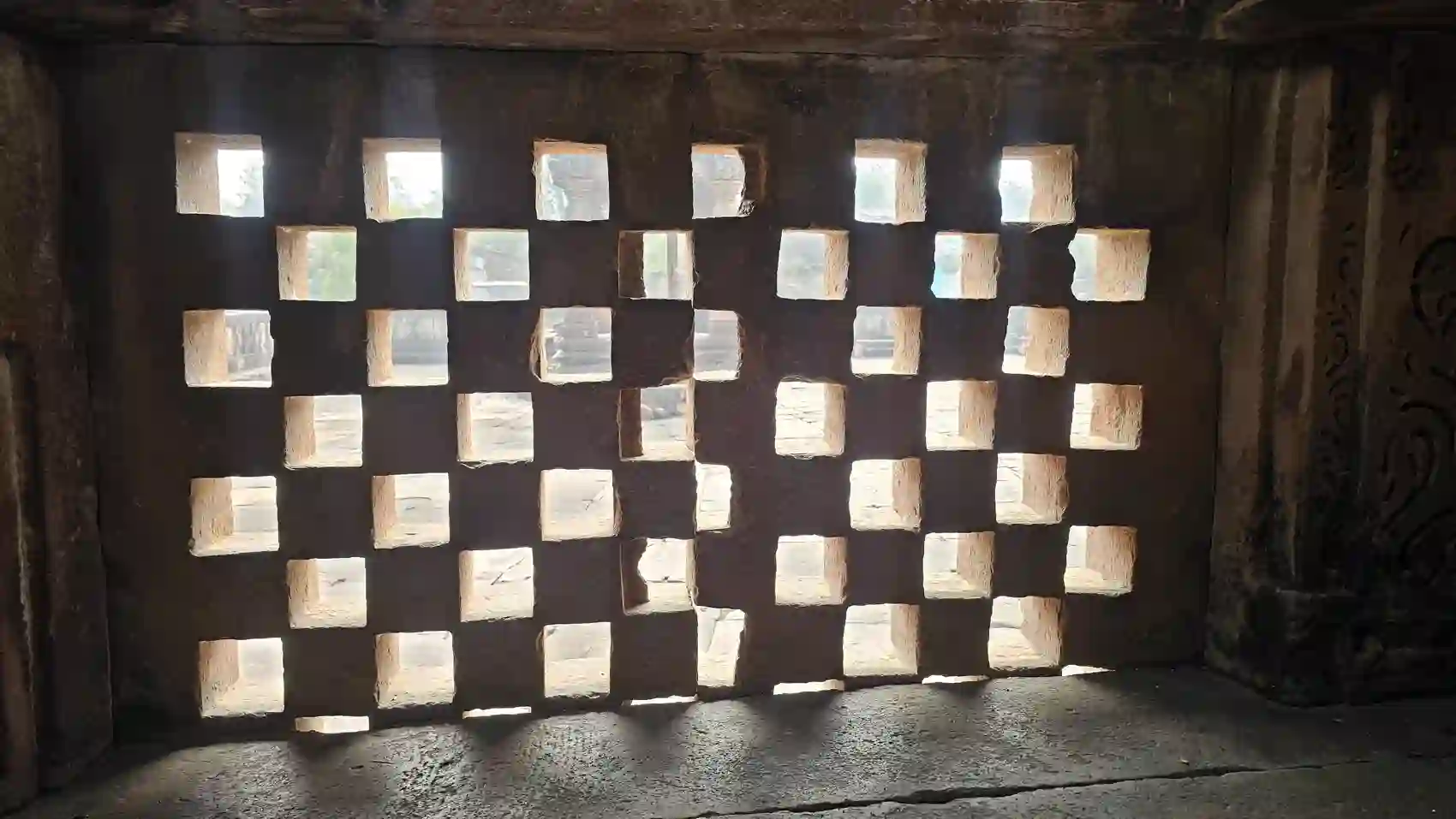 Sunlight through a carved stone lattice window inside the Neelkantheshwar temple