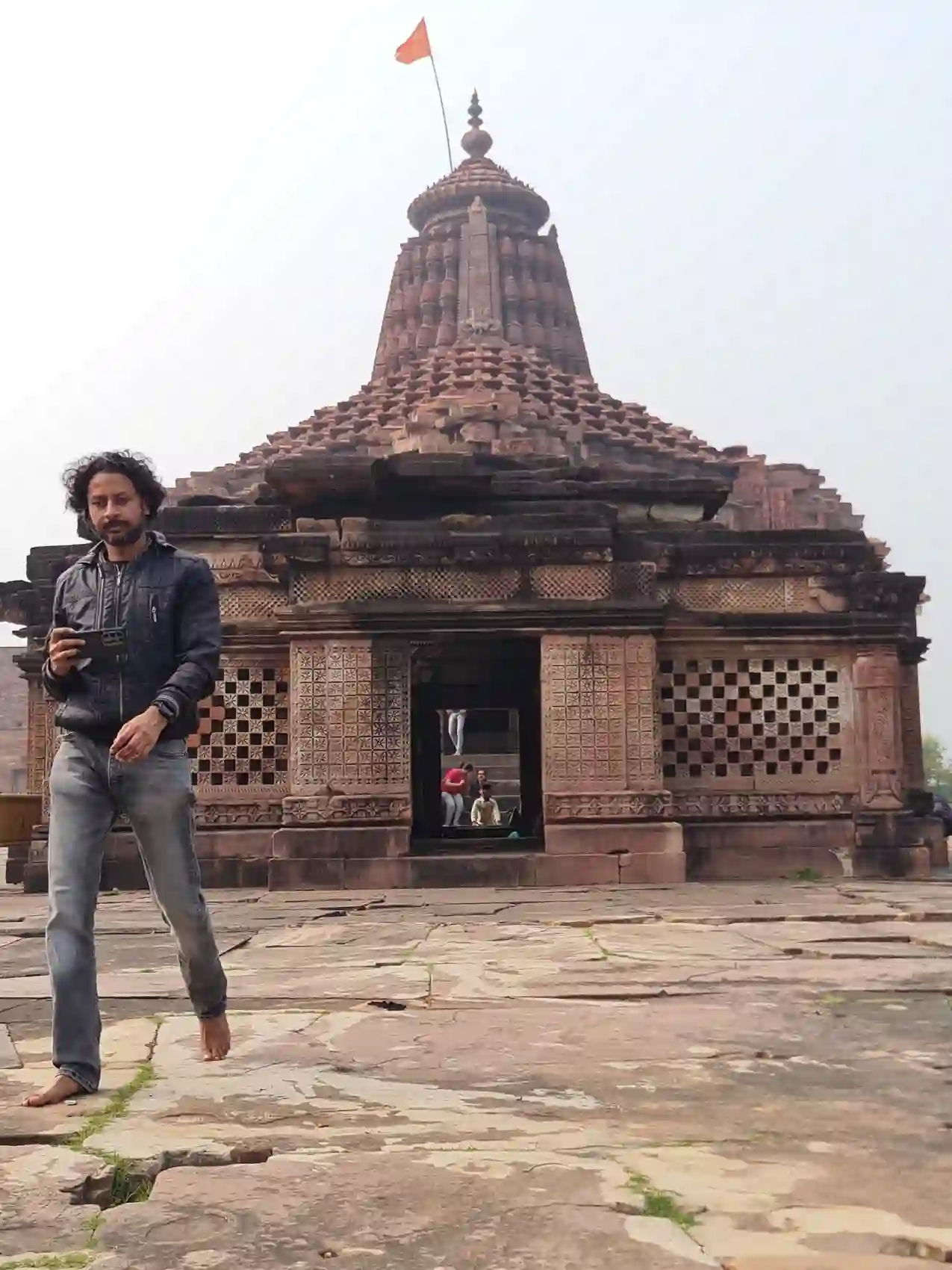 A visitor standing barefoot before the carved sandstone Neelkantheshwar temple at Udaypur