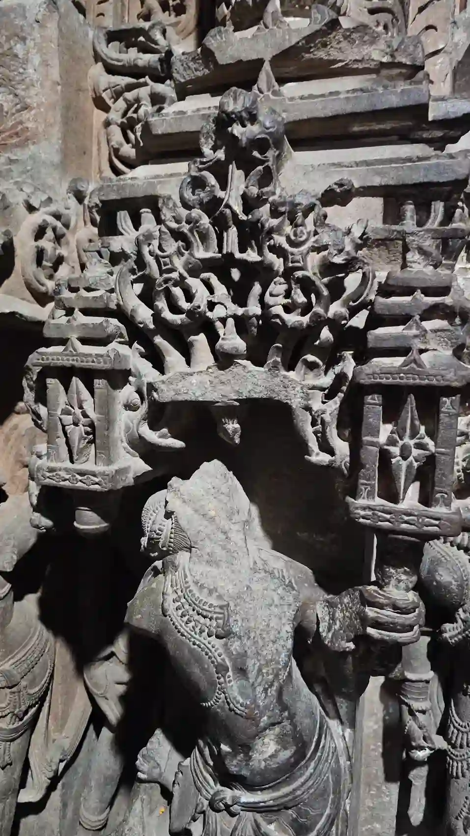 A carved reclining figure and lattice detail inside the Neelkantheshwar temple