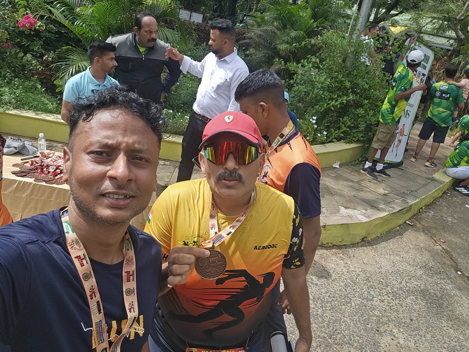 Two happy finishers showing their Pachmarhi Monsoon Marathon 21K medals at the finish area